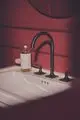 Waschtisch mit moderner Armatur von Ideal Standard in Metallic-Farbe, ergänzt durch einen Spiegelschrank und eine Seifenspenderflasche auf der Ablage.